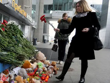 Seorang wanita meletakkan bunga di depan Bandara Internasional St. Petersburg di Rusia, Minggu (1/11). ini sebagai bentuk penghormatan kepada para penumpang yang menjadi korban jatuhnya pesawat Kogalymavia di Mesir. (AFP PHOTO/OLGA MALTSEVA)
