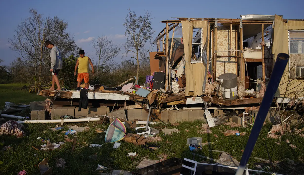 Aiden Locobon (kiri) dan Rogelio Paredes melihat-lihat sisa-sisa rumah keluarga mereka yang hancur akibat hantaman Badai Ida di Dulac, Louisiana, Sabtu (4/9/2021). Jumlah korban tewas akibat Badai Ida di negara bagian Louisiana, AS, pada Sabtu (4/9) bertambah menjadi 12 orang. (AP Photo/John Locher)