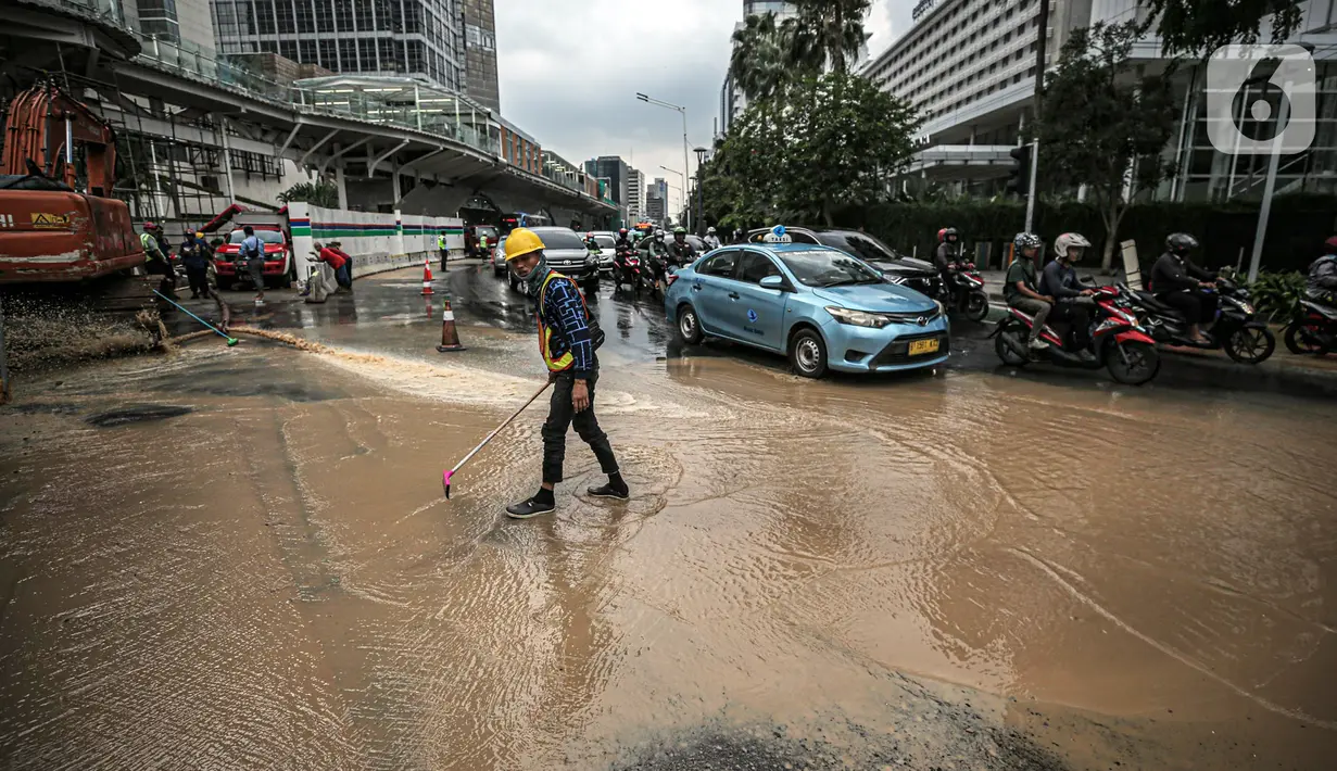 Petugas membersihkan jalan dari genangan air akibat kebocoran saluran pipa air di kawasan Bundaran Hotel Indonesia (HI), Jakarta, Selasa (11/10/2022). Kebocoran pipa air diduga terimbas proyek revitalisasi Halte Bundaran Hotel Indonesia. (Liputan6.com/Faizal Fanani)