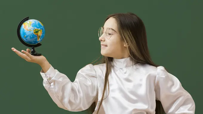 Seorang anak perempuan sedang berkacak pinggang dan memegang sebuah globe (Foto Dok: Freepik/freepik)