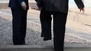 Pemimpin Korea Utara, Kim Jong-un disaksikan Presiden Korea Selatan, Moon Jae-in melintasi perbatasan yang ditandai dengan tembok beton pendek setinggi mata kaki di Zona Demiliterisasi (DMZ), Panmunjom, Jumat (27/4).  (Korea Summit Press Pool via AP)