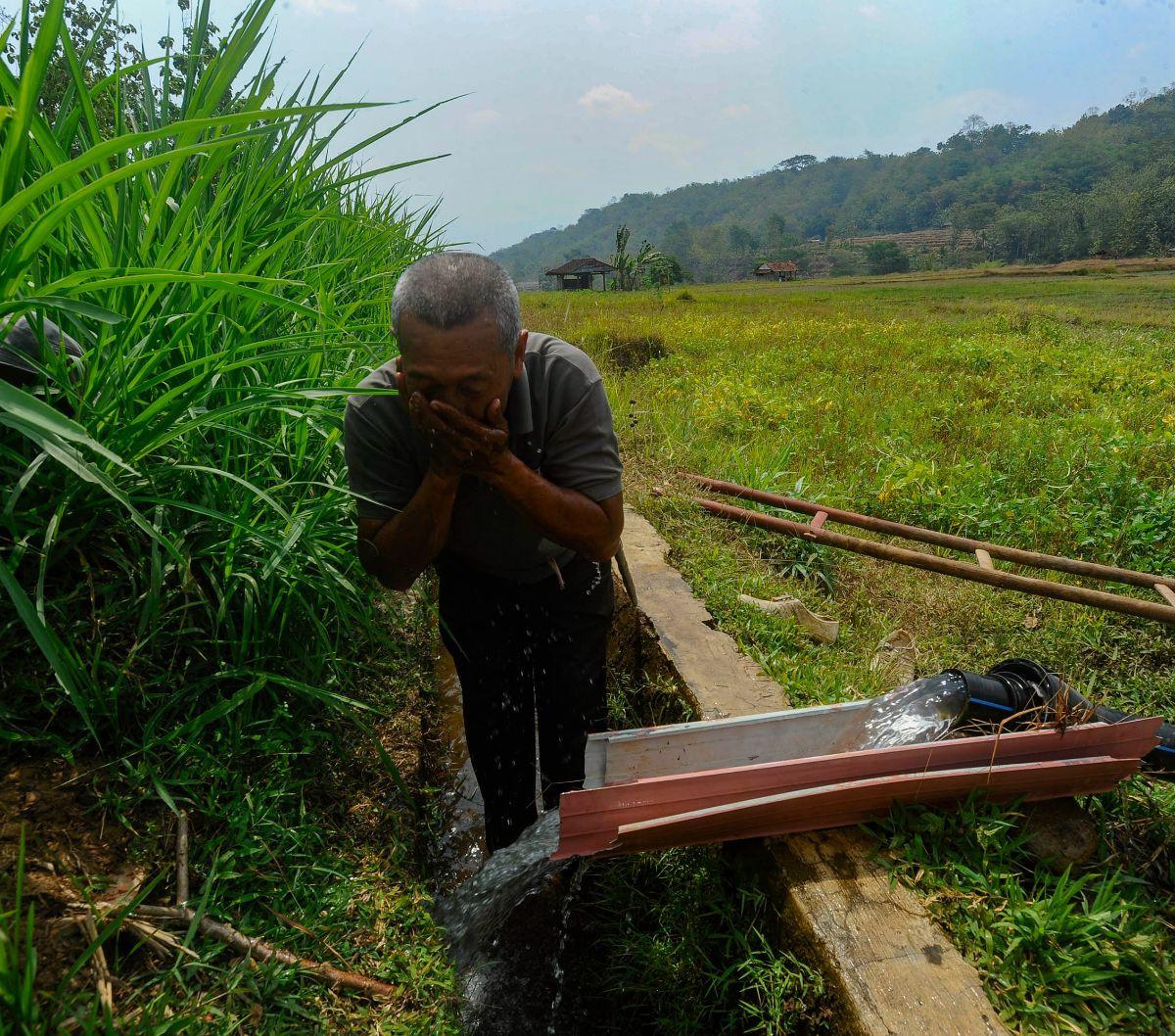 Seorang petani membersihkan wajah dengan air yang dipompa dari sungai saat mengairi lahan pertaniannya di Cikaduwetan Kabupaten Kuningan, Jawa Barat , Rabu (23/08/2023).