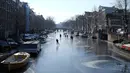 Orang-orang berseluncur dan berjalan melintasi permukaan kanal Prinsengracht yang membeku di Amsterdam, Belanda, Jumat (2/3). Banyak juga wisatawan yang melakukan swafoto untuk mengabadikan momen langka ini. (AP/Mike Corder)