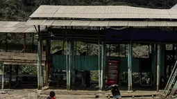 Seorang warga beraktivitas saat gunung berapi Gunung Sinabung yang memuntahkan abu tebal di Karo, Sumatra Utara (18/12). Setelah periode tidak aktif, Gunung Sinabung meletus pada tahun 2013, dan tetap sangat aktif sampai sekarang. (AFP Photo/Ivan Damanik)