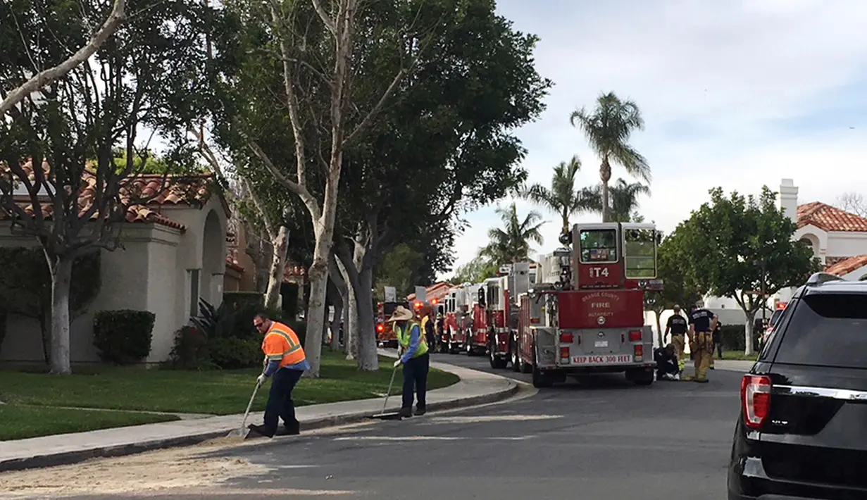 Petugas membersihkan puing helikopter yang jatuh menghantam sebuah rumah di Newport Beach, California, Selasa (30/1). Tiga orang tewas dan dua lainnya terluka dalam kecelakaan helikopter yang jatuh di lingkungan perumahan tersebut. (AP Photo/Amy Taxin)