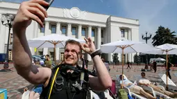 Aktivis tampak berselfie menggunakan baju menyelam di depan gedung parlemen Kiev, Ukraina, (12/7). Aksi ini mereka memprotes masa reses parlemen Kiev.( REUTERS / Valentyn Ogirenko)