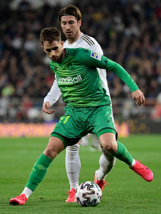 Bek Real Madrid, Sergio Ramos (kanan) berebut bola dengan pemain depan Real Sociedad, Adnan Januzaj pada laga perempat final Copa del Rey di Santiago Bernabeu, Kamis (6/2/2020). Real Madrid gagal melaju ke semifinal Copa del Rey setelah dibungkam Real Sociedad dengan skor 3-4. (JAVIER SORIANO/AFP)