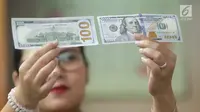 Teller menunjukkan mata uang dolar di Jakarta, Jumat (2/2). Deputi Gubernur Senior BI Mirza Adityaswara mengatakan, posisi nilai tukar rupiah terhadap dolar Amerika Serikat yang berada di level Rp13.700 hingga Rp13.800.(Liputan6.com/Angga Yuniar)