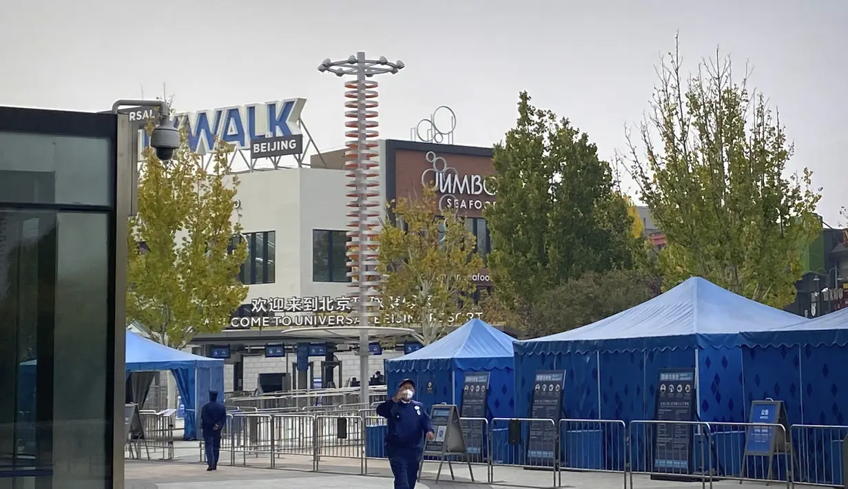Seorang penjaga keamanan yang mengenakan masker memberi isyarat di luar resor Universal Studios Beijing, yang menurut pemberitahuan ditutup untuk pengendalian epidemi, di Beijing, Rabu (26/10/2022). Kota Shanghai di China mulai memberikan vaksin COVID-19 yang dapat dihirup pada hari Rabu di tempat yang tampaknya menjadi yang pertama di dunia. (AP Photo/Mark Schiefelbein)