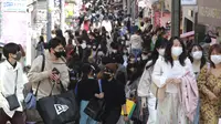 Orang-orang yang memakai masker wajah untuk melindungi dari penyebaran virus corona berjalan di sebuah jalan di Tokyo, Rabu (31/3/2021).  Ibukota Jepang mengonfirmasi lebih dari 410 kasus virus corona baru pada hari Rabu. (AP Photo/Koji Sasahara)