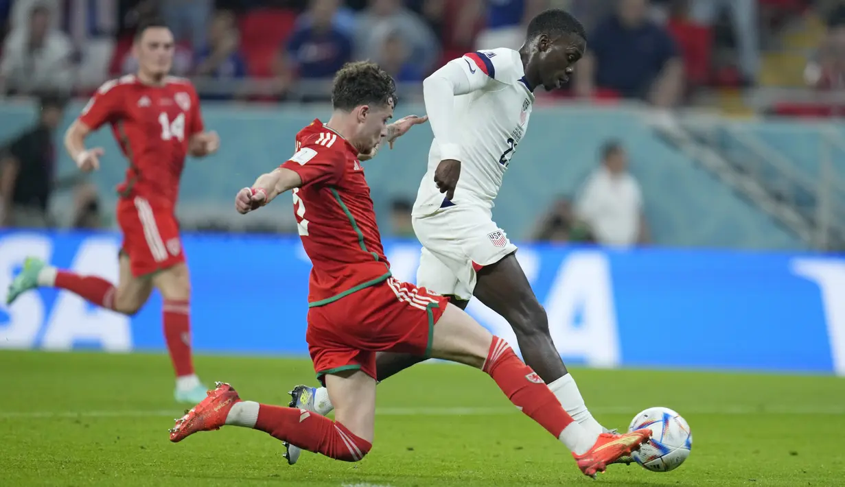 <p>Penyerang Timnas Amerika Serikat Timothy Weah (kanan) mencetak gol pertama timnya pada pertandingan sepak bola Grup B Piala Dunia Qatar 2022 antara Amerika Serikat dan Wales di Stadion Ahmad Bin Ali di Al-Rayyan, Doha, Qatar, Senin (21/11/2022). Sebelum menjadi orang nomor satu di Liberia, sang ayah pernah menjadi pemain terbaik AC Milan. (AP Photo/Ashley Landis)</p>