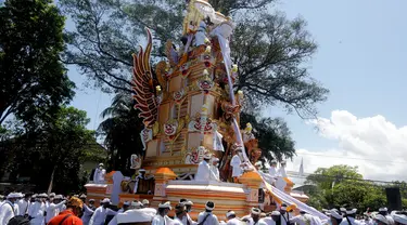 Kerumunan orang menyaksikan arak-arakan menara usungan jenazah Ida Pedanda Nabe Gede Dwija Ngenjung saat upacara Ngaben di Denpasar, Bali, Jumat (8/10/2021). Upacara Ngaben itu sebagai penghormatan terakhir terhadap seorang pemuka agama Hindu di Bali. (AP Photo/Firdia Lisnawati)