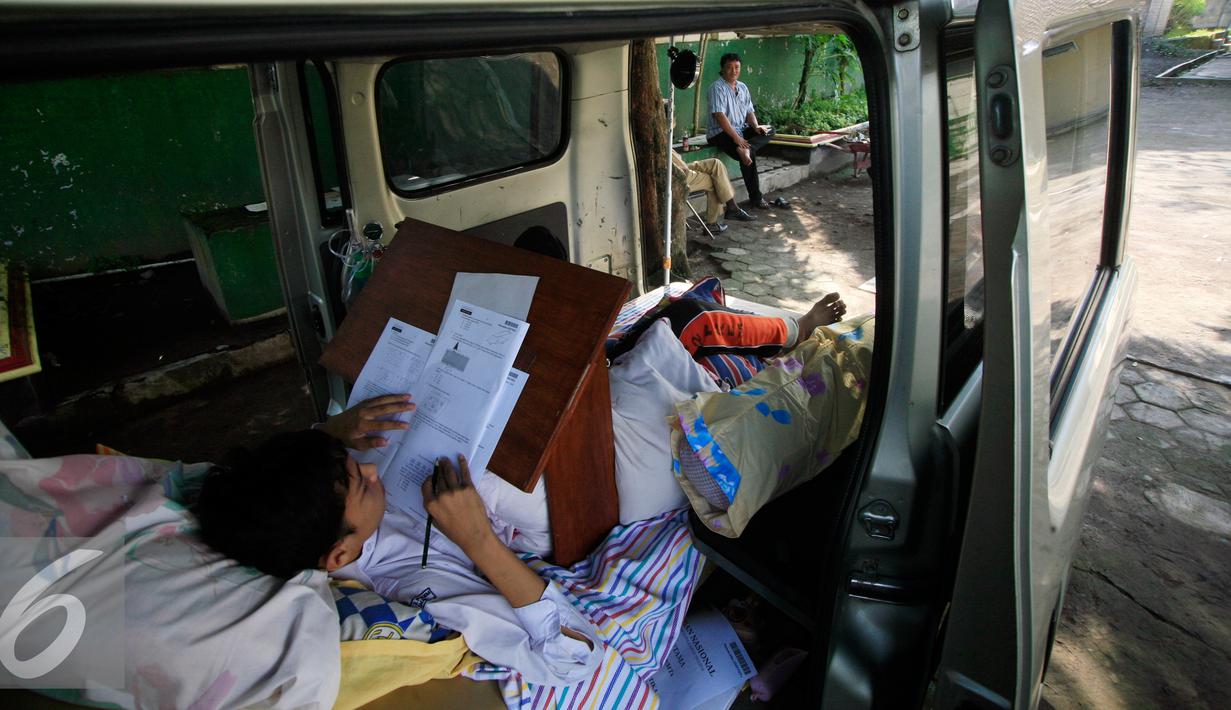 Seorang siswa SMP N 2 Pakem ,Fitrian (14) terlihat serius mengerjakan soal Ujian Nasional di halaman SMP N 2 Pakem, Sleman, (10/5). Akibat kecelakaan,Fitrian terpaksa melaksanakan UN di dalam mobil ambulans . (Liputan6.com/Boy Harjanto)