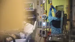 Pekerja medis merawat pasien covid-19 di ruang tekanan negatif di bangsal ICU UMass Memorial Medical Center di Worcester, Massachusetts, Selasa (4/1/2022). Menurut data, Massachusetts saat ini memiliki 2.221 rawat inap pasien covid dengan 402 di kamar ICU dan 245 diintubasi. (Joseph Prezioso/AFP)