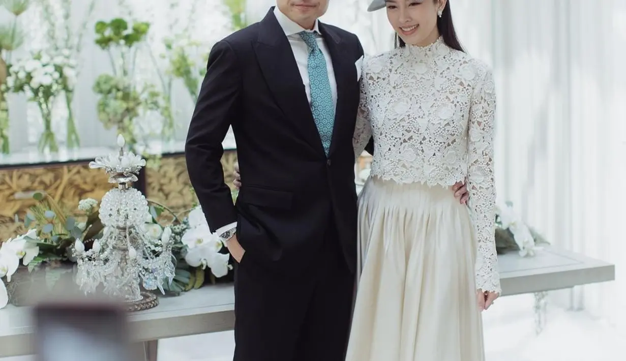 Nong Poy memilih gaun pengantin dengan atasan renda warna putih dan rok aksen ruffle. Ia mengenakan aksesori fascinator ala keluarga kerajaan.  [@niyadarweddinganswer]