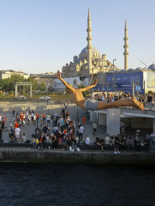 Seorang pria menyelam ke perairan Tanduk Emas dengan latar belakang Yeni Cami, di Istanbul, Selasa (27/7/2021). Turki telah mencatat lebih dari 15.000 kasus virus corona baru, karena jumlah infeksi yang terus meningkat. (AP Photo/Mucahid Yapici)