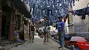 Anak-anak bermain bola di sebuah gang dengan jeans tergantung untuk dijual di pasar pakaian bekas di Kolkata, India, 10 Maret 2016. Kota ini memiliki kekurangan perumahan yang parah, setidaknya 1 juta orang tidur di jalan. (REUTERS/Rupak De Chowdhuri)