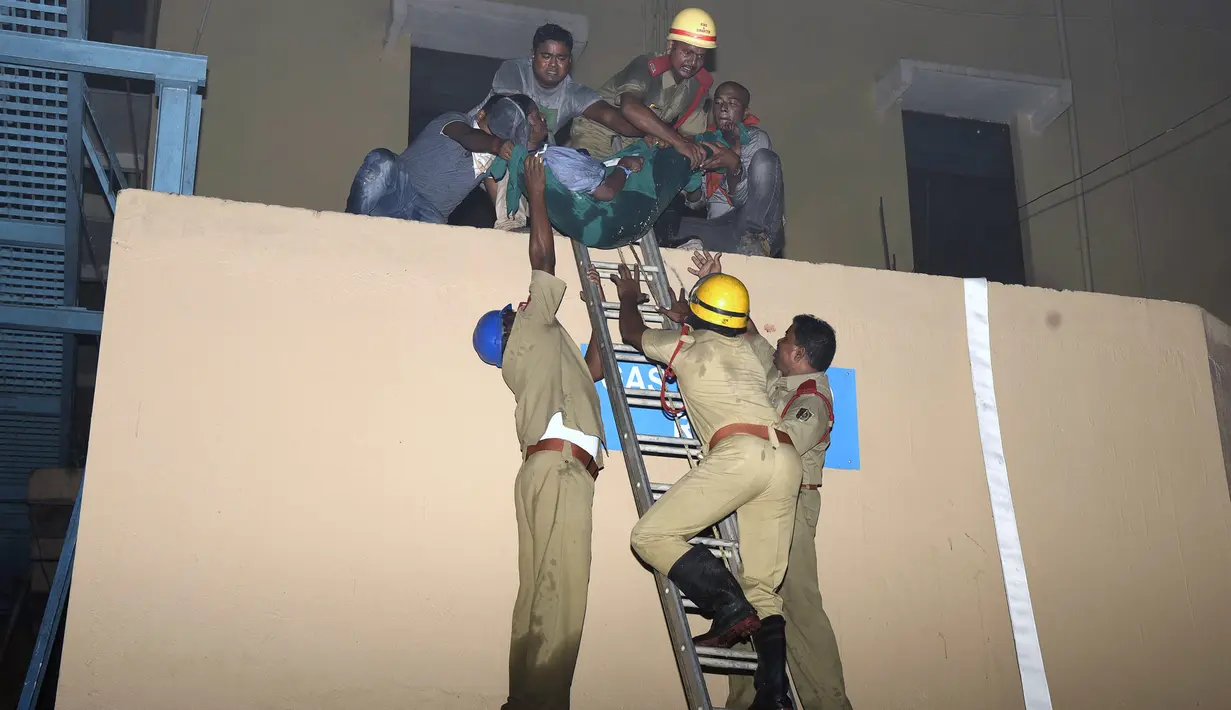 Salah satu korban berhasil dievakuasi oleh petugas pemadam saat kebakaran melanda rumah sakit SUM Bhubaneshwar di Odisha, India Timur, Senin (17/10). Sebagian besar korban dilaporkan meninggal karena kehabisan napas akibat menghirup asap. (AFP)