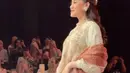 Untuk sentuhan lebih dramatis, ia memadukannya dengan selendang merah bata yang semakin memperkuat kesan anggun. [@thariqhalilintar/@ochiipramita].