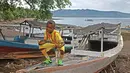Seorang Anak duduk diatas perahu dengan jersey Barcelona siap untuk bermain sepak bola di Alor, Nusa Tenggara Timur. (Bola.com/Nicklas Hanoatubun)