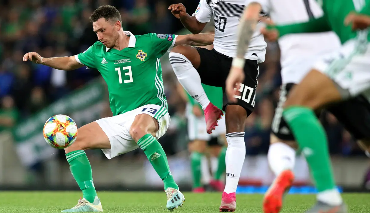 Gelandang Irlandia Utara, Corry Evans (kiri) menahan gelandang Jerman, Serge Gnabry (kanan) selama pertandingan kualifikasi Euro 2020 di Windsor Park, Belfast, Senin (9/9/2019). Jerman berhasil merebut puncak klasemen grup C kualifikasi Euro 2020 usai mengalahkan Irlandia Utara 2-0. (Paul Faith/AFP)