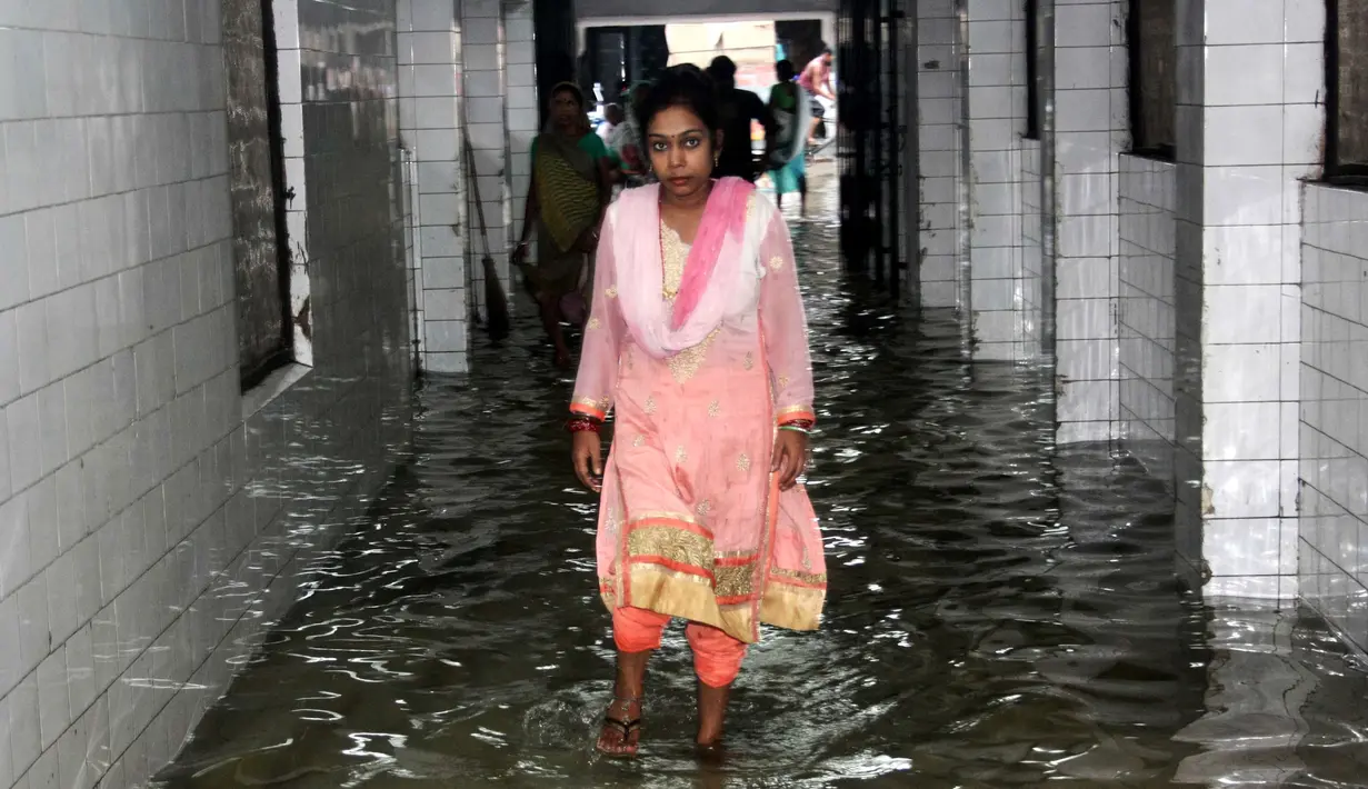 Seorang wanita berjalan di koridor rumah sakit yang tergenang banjir di Nalanda Medical College Hospital, daerah Bihar, India, 29 Juli 2018. Rumah sakit itu digenangi air kotor dengan sejumlah ikan terlihat berenang memenuhi lantai. (AFP PHOTO)