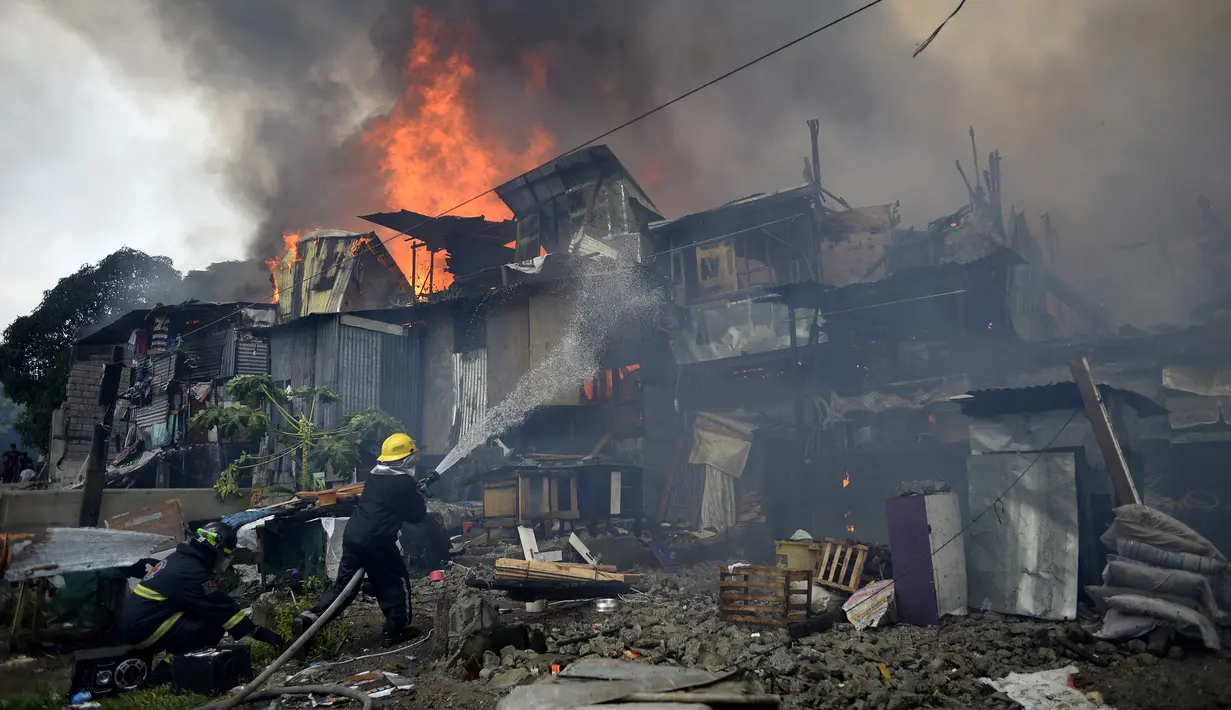 Petugas pemadam kebakaran berusaha memadamkan api yang membakar kawasan kumuh di Manila, Filipina (11/8). (AFP Photo/Noel Celis)