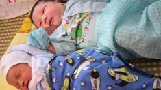 Seorang bayi laki-laki, Tran Tien Quoc (atas) sedang tidur di samping bayi laki-laki tidak dikenal di pusat kesehatan Vinh Tuong, provinsi Vinh Phuc, Minggu (15/10). Ibu asal Vietnam melahirkan bayi laki-laki itu dengan berat 7,1 kilogram. (LE PHUONG/AFP)
