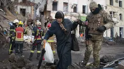 Relawan Pasukan Pertahanan Teritorial Ukraina membantu seorang perempuan menyeberang jalan di Kharkiv, 16 Maret 2022. Invasi Rusia ke Ukraina memasuki hari ke-21. Berbagai upaya negosiasi menuju kompromi telah dilakukan demi menuju perdamaian di antara kedua belah pihak. (AP Photo/Andrew Marienko)