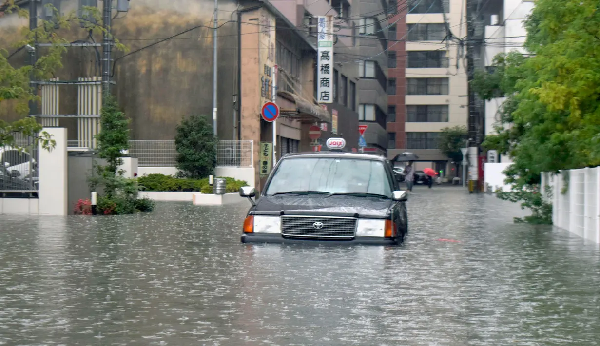 Sebuah taksi terjebak banjir di Saga, Jepang, Rabu (28/8/2019). Sejumlah lokasi rawan banjir dan tanah longsor di Jepang saat ini mencakup Saga, Fukuoka, dan Nagasaki di utara Kyushu. (Kyodo News via AP)