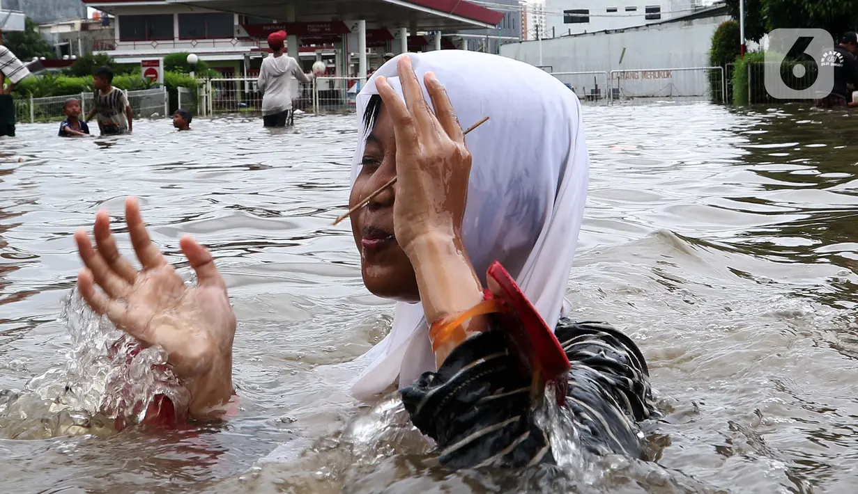 Seorang anak bermain banjir yang merendam kawasan Green Garden, Jakarta Barat, Selasa (25/2/2020). Hujan yang mengguyur kawasan Jakarta membuat kawasan tersebut tergenang banjir setinggi 60-80 cm. (Liputan6.com/Johan Tallo)