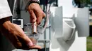 Ilmuwan Belgia, Sebastiaan Derese menuangkan air dari mesin buatannya yang bisa mengubah air seni menjadi air yang layak diminum dan menjadi pupuk dengan bantuan energi matahari, di University of Ghent, Belgia, Selasa (26/7). (REUTERS/Francois Lenoir)
