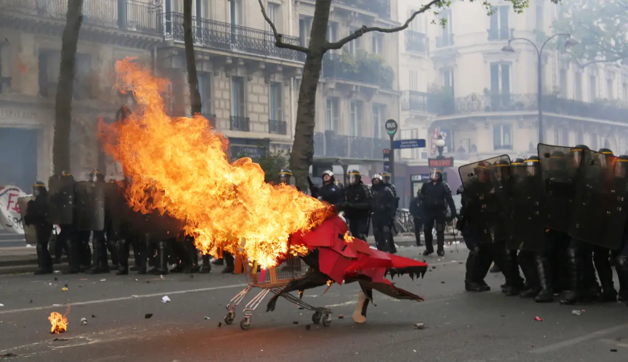 Pengunjuk rasa mendorong troli yang terbakar ke arah polisi anti huru hara Prancis selama demonstrasi perayaan May Day di Paris,Senin (1/5). Hari Buruh Internasional di Paris, diwarnai bentrokan antara pengunjuk rasa dengan polisi. (Zakaria ABDELKAFI/AFP)