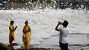 Pengunjung berfoto dengan latar belakang busa yang memenuhi sungai Yamuna di kota New Delhi, India, 23 September 2018. Akibat pertumbuhan populasi dan industrialisasi, Sungai Yamuna menjadi salah satu sungai paling tercemar di dunia. (AFP/Dominique FAGET)