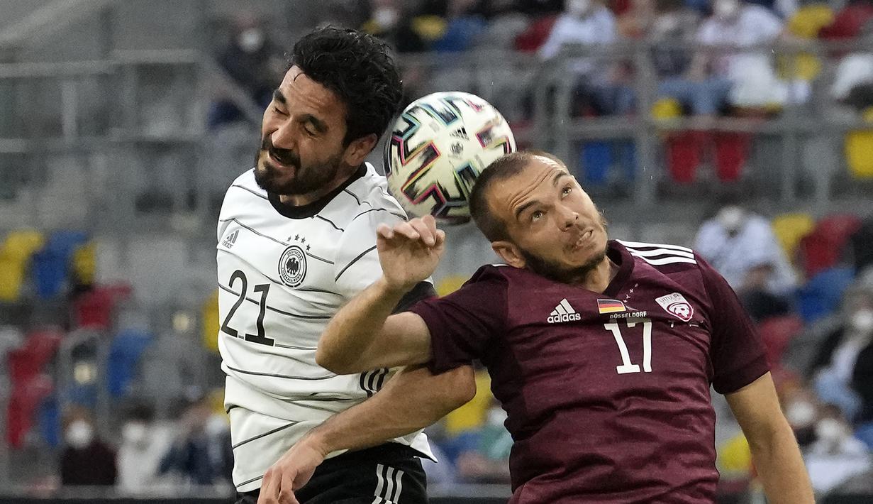 Gelandang Jerman, Ilkay Gundogan (kiri) berduel udara dengan gelandang Latvia, Arturs Zjuzins dalam laga uji coba menjelang Euro 2020 (Euro 2021) di Merkur Spiel Arena, Duesseldorf, Senin (7/6/2021). Jerman menang 7-1 atas Latvia. (AP/Martin Meissner)