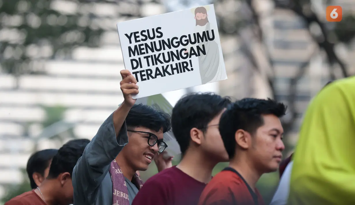 Seorang penonton membawa poster bertema religius saat Jakarta Running Festival (JRF) 2026 berlangsung di sepanjang lintasan Jalan Jenderal Sudirman, Jakarta, Sabtu (24/10/2026). (KLY/Budy Santoso)