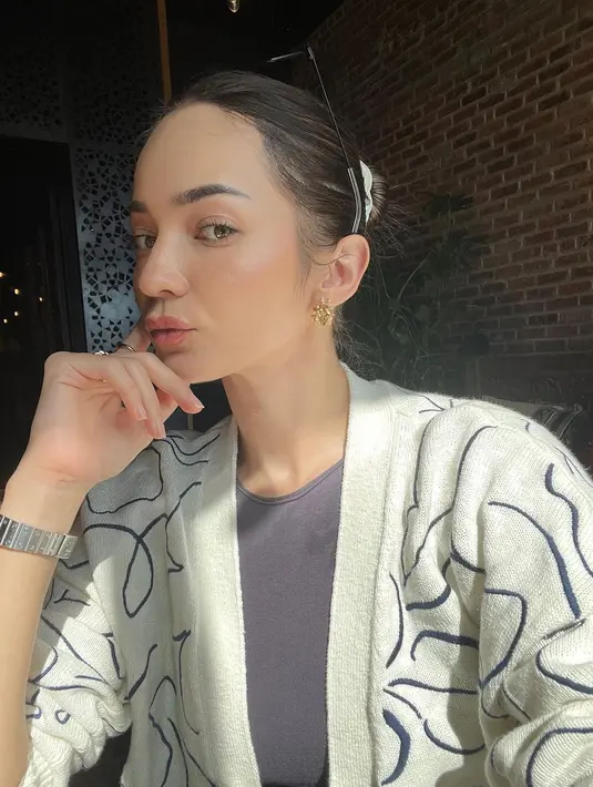 Nongkrong di sebuah kafe, Enzy Storia terlihat santai mengenakan haltertop dan cardigan wol [@enzystoria]