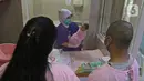 Perawat menunjukkan seorang bayi kepada orangtuanya setelah selesai dimandikan di RSIA Tambak, Jakarta, Kamis (18/02/2021). Melatih para ibu baru untuk memandikan bayi pertama tersebut dilakukan dengan menerapkan protokol kesehatan ketat. (Liputan6.com/Herman Zakharia)