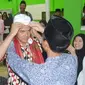 Seorang santri memakaikan peci atau kopyah kepada Ganjar Pranowo saat kunjungan ke pesantren El Bayan, Majenang, Cilacap. (Liputan6.com/Muhamad Ridlo)