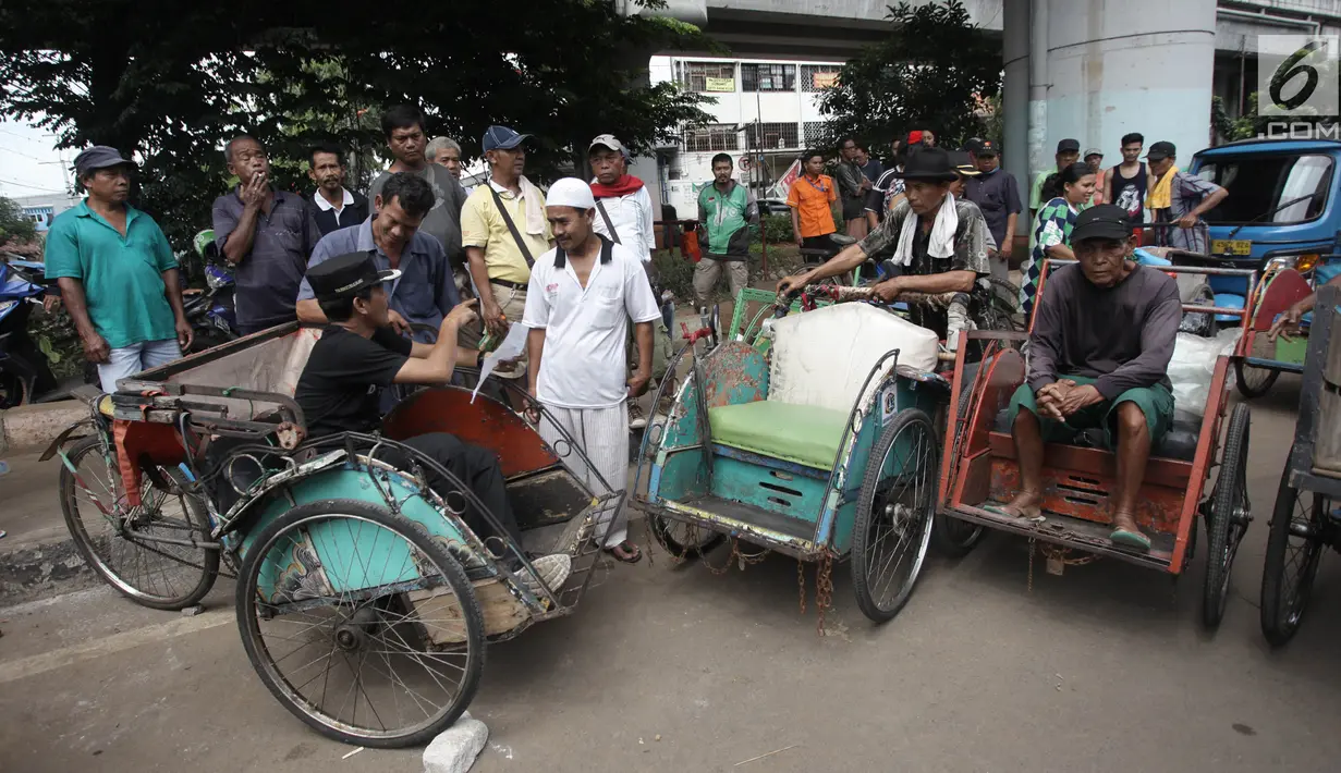 Petugas melakukan pendataan terhadap tukang becak di Kolong Flyover Bandengan Utara, Jakarta, Kamis (25/1). Becak-becak yang sudah didata ditempelkan stiker berlogo Pemprov DKI dan bertuliskan "Angkutan Orang Kawasan Tertentu" (Liputan6.com/Arya Manggala)