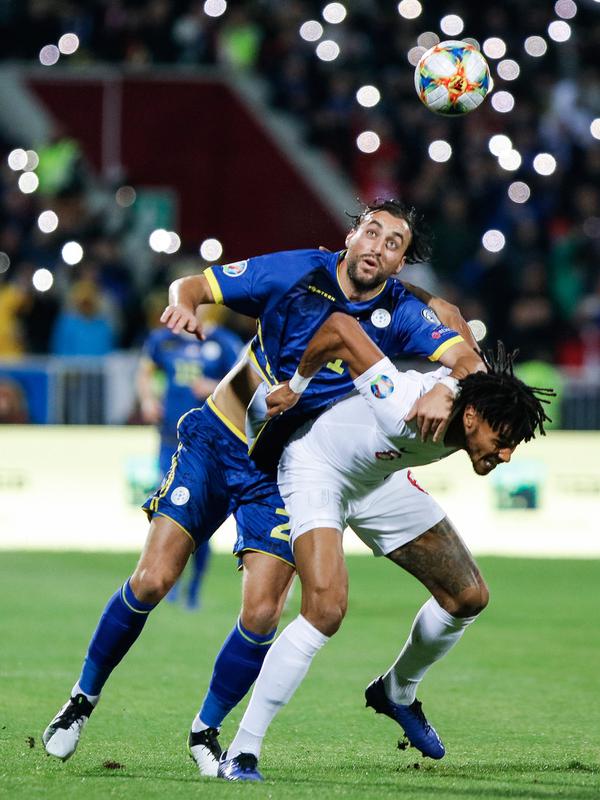 Pemain Timnas Kosovo Atdhe Nuhiu berebut bola dengan dengan pemain belakang Timnas Inggris Harry Maguire pada laga Grup A kualifikasi Piala Eropa 2020 di Fadil Vokrri Stadium, Minggu (17/11/2019). Timnas Inggris mampu meraih kemenangan telak 4-0 atas timnas Kosovo. (Armend NIMANI / AFP)