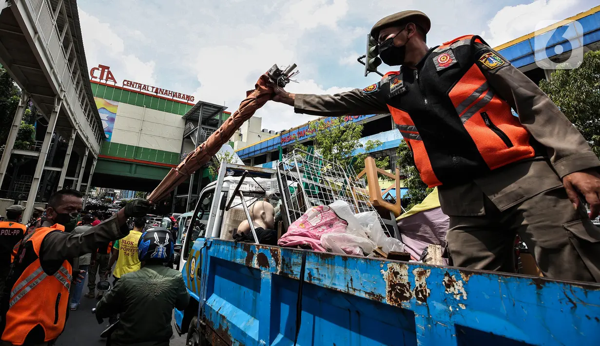 Aparat gabungan mengangkut dagangan pedagang yang berjualan di trotoar di kawasan Tanah Abang, Jakarta, Minggu (2/5/2021). Selain merazia barang dagangan pedagang, aparat gabungan juga menegur warga yang tidak menerapkan protokol kesehatan. (Liputan6.com/Johan Tallo)