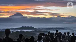 Wisatawan menikmati matahari terbit atau sunrise dengan latar belakang Candi Borobudur di Punthuk Setumbu, Karangrejo, Magelang, Jawa Tengah, Senin (16/5/2022). Punthuk Setumbu menjadi destinasi favorit di Jawa Tengah, terlebih saat libur Waisak yang terkenal dengan keindahan alam Candi Borobudur dan sekitarnya saat matahari terbit. (merdeka.com/Iqbal S. Nugroho)
