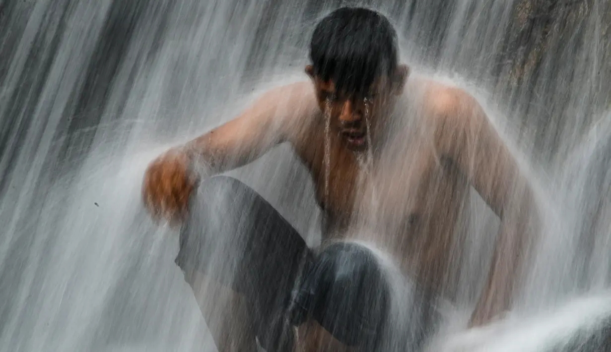Seorang pemuda mendinginkan diri di air terjun di Samadua, Provinsi Aceh pada 9 Juli 2020. Aceh punya banyak destinasi wisata alam mempesona yang patut dikunjungi. (Photo by CHAIDEER MAHYUDDIN / AFP)