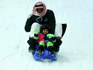 Seorang pria dan anaknya berseluncur menikmati bermain salju di Snow City di Mall Al Othaim, Riyadh, Arab Saudi (26/7). (REUTERS/Faisal Al Nasser)