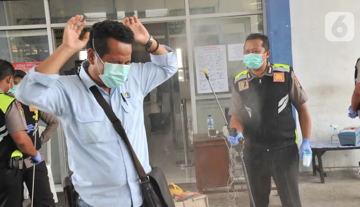Petugas Direktorat Lalu Lintas Polda Jawa Tengah menyemprotkan disinfektan ke calon penumpang saat sterilisasi puluhan angkutan bus yang masuk di Terminal Bawen, Jumat (27/3/2020). (Liputan6.com/Gholib)