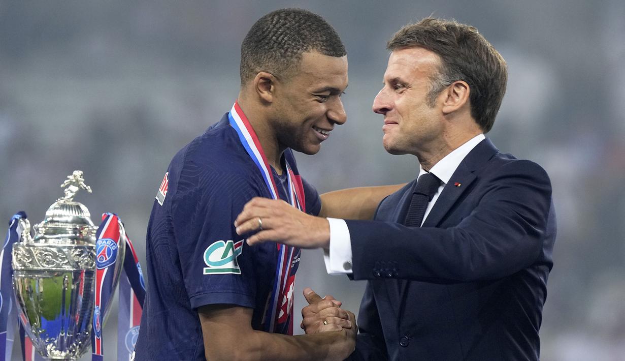 Pemain PSG, Kylian Mbappe (kiri) bersalaman dengan Presiden Prancis, Emmanuel Macron saat upacara penyerahan trofi Coupe De France 2023/2024 di Stade Pierre-Mauroy, Villeneuve-d'Ascq, Prancis, Minggu (26/05/2024) WIB. PSG menang dengan skor 2-1 atas Olympique Lyon pada babak final. (AP Photo/Michel Euler)