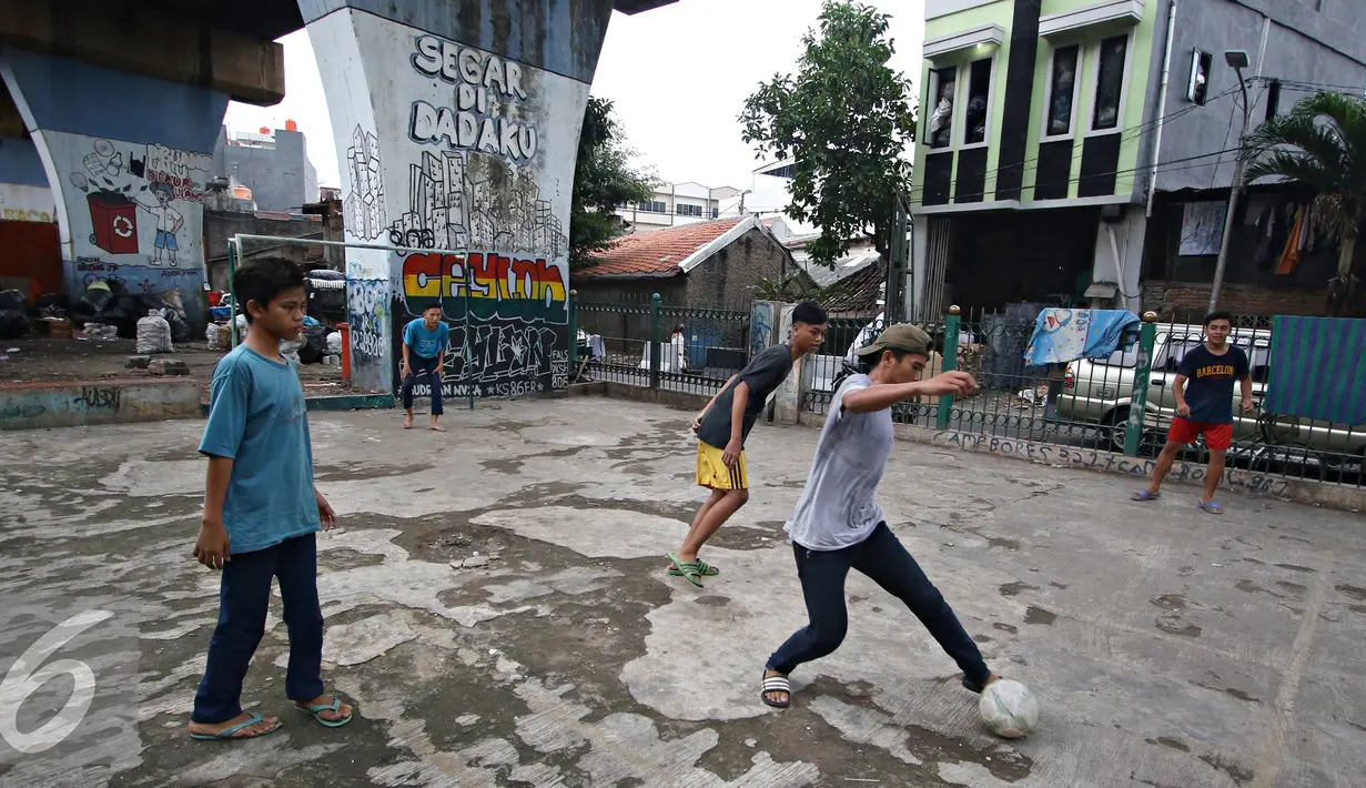 Seorang remaja saat mengiring bola saat bermain di kolong rel kereta kawasan Juanda, Jakarta, Jumat (27/5). Tidak tersedianya ruang terbuka menyebabkan lahan tersebut dijadikan tempat bersosialisasi bagi warga. (Liputan6.com/Immanuel Antonius)