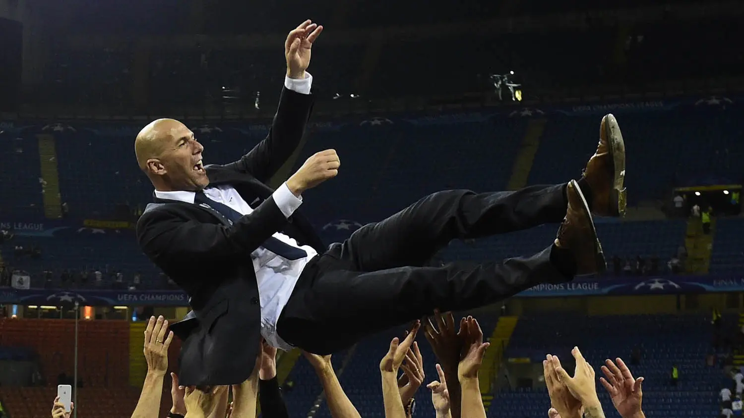 Pelatih Real Madrid, Zinedine Zidane, diangkat oleh anak asuhnya usai meraih gelar Liga Champions di Stadion San Siro, Milan, Sabtu (28/5/2016). (AFP/Pierre-Philippe Marcou)