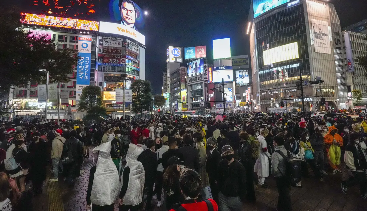 Penonton Halloween berjalan-jalan dengan kostum saat ribuan orang berkumpul di distrik Shibuya, area berkumpul yang populer untuk Halloween, Minggu (31/10/2021). Daerah di sekitar Stasiun Shibuya dipadati anak-anak muda yang berdandan selama Halloween setiap tahun. (AP Photo /Kiichiro Sato)